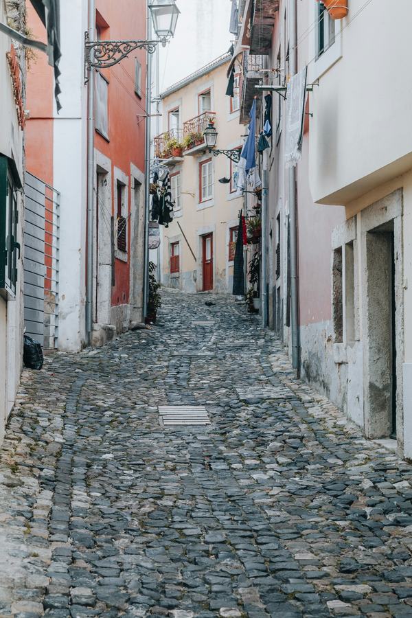 A narrow cobbled alley with washing hung between the houses, nobody in it