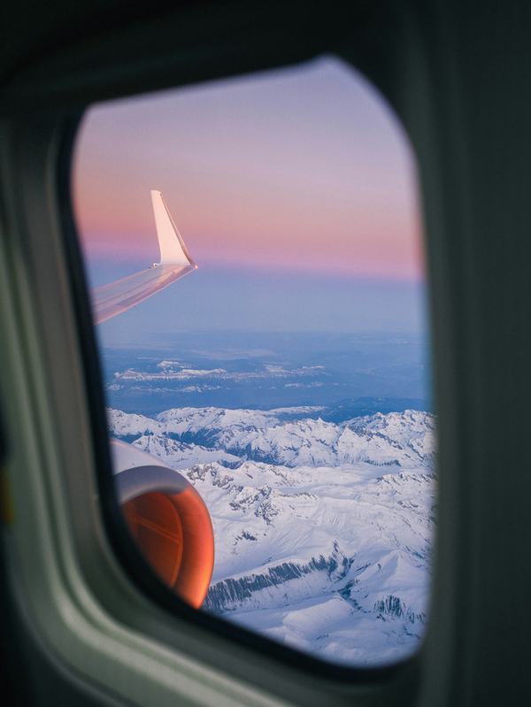An aircraft wing over snow-covered mountains, seen from a window seat